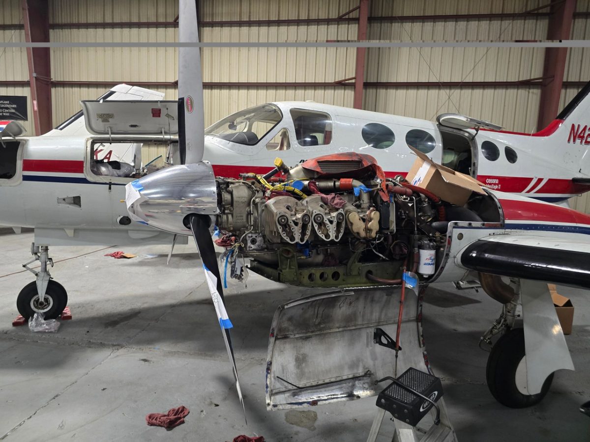 Twin-engine aircraft with engine cowling removed for maintenance in a hangar